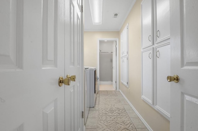 hall featuring crown molding, light tile patterned floors, and washer and dryer