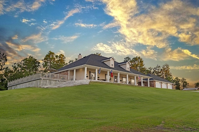 back house at dusk with a lawn and covered porch