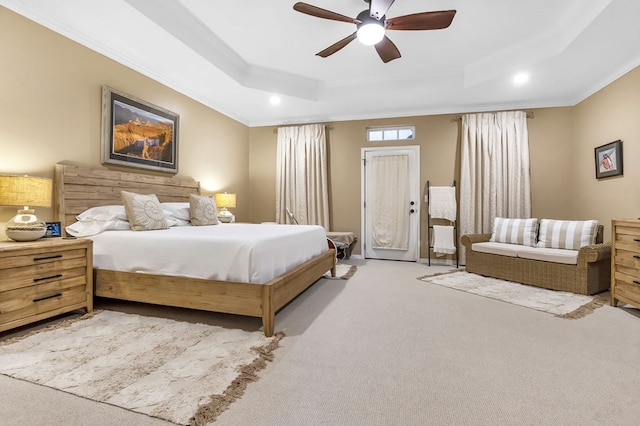 carpeted bedroom featuring ceiling fan, ornamental molding, and a tray ceiling