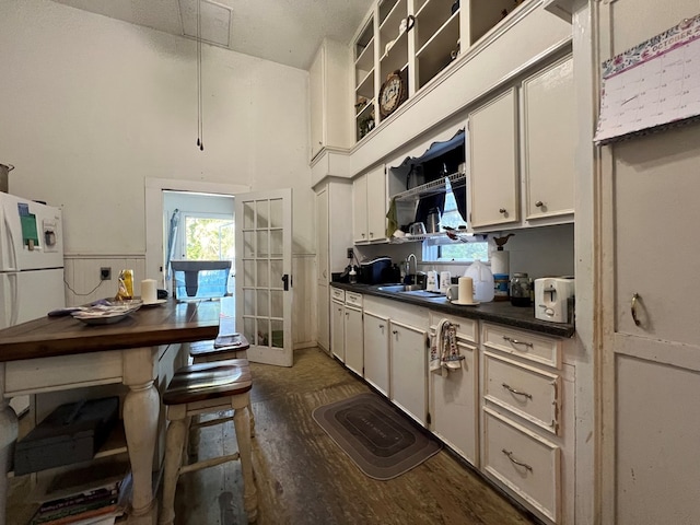 kitchen featuring white cabinets, white refrigerator, sink, and dark wood-type flooring