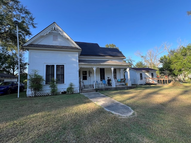 view of front of home featuring covered porch, a front lawn, and solar panels