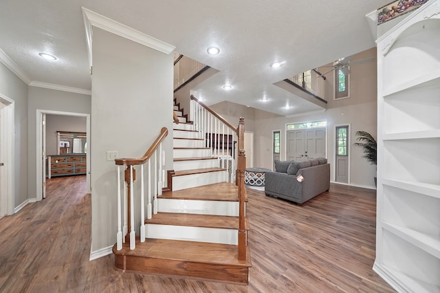 stairs with hardwood / wood-style floors, ornamental molding, and a textured ceiling