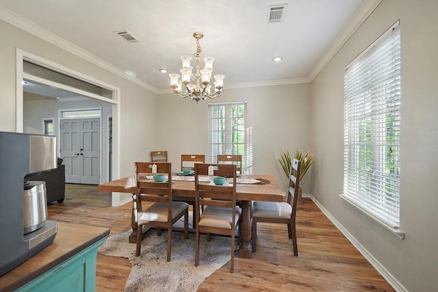 dining room with wood-type flooring, ornamental molding, and a notable chandelier