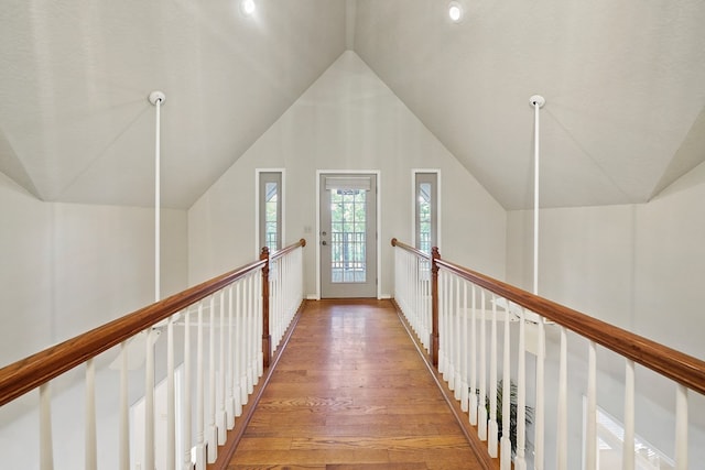 hallway with hardwood / wood-style floors and vaulted ceiling