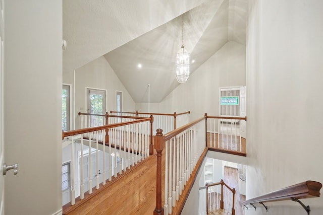 staircase featuring an inviting chandelier, lofted ceiling, and hardwood / wood-style flooring