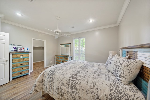 bedroom with a walk in closet, light hardwood / wood-style flooring, ceiling fan, ornamental molding, and a closet