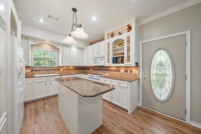 kitchen with a kitchen island, light hardwood / wood-style flooring, dark stone counters, white appliances, and white cabinets