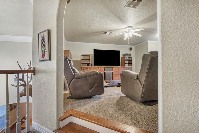 living room featuring a textured ceiling, ceiling fan, and crown molding