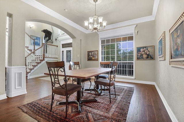 dining space featuring a notable chandelier, ornamental molding, and dark wood-type flooring