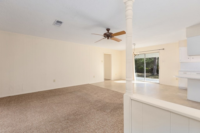 unfurnished living room with decorative columns, ceiling fan with notable chandelier, light carpet, and a textured ceiling