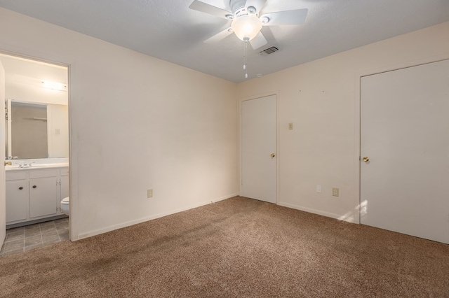 unfurnished bedroom featuring connected bathroom, carpet floors, and ceiling fan