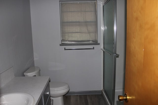 full bathroom featuring a shower with door, toilet, wood finished floors, and vanity