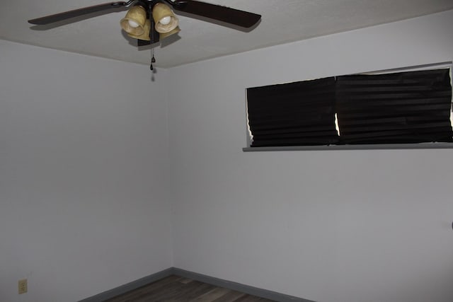 spare room featuring dark wood-style floors, baseboards, and ceiling fan