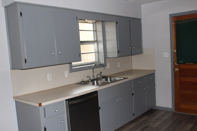 kitchen featuring dark wood finished floors, dishwashing machine, gray cabinets, and a sink