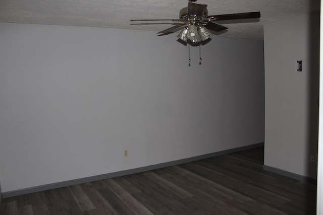 empty room featuring dark wood-type flooring, a ceiling fan, baseboards, and a textured ceiling
