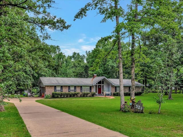 single story home with concrete driveway, brick siding, a front yard, and a chimney