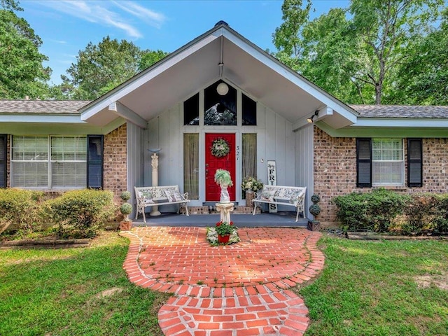 property entrance with brick siding, a lawn, board and batten siding, and a porch