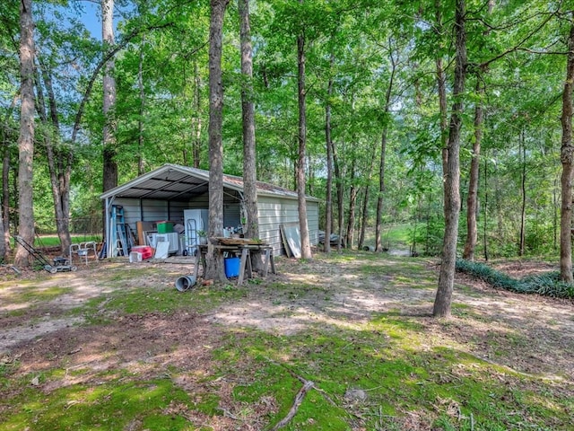 view of yard featuring a garage, an outdoor structure, and a wooded view