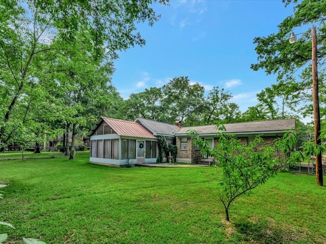 rear view of property featuring brick siding, a yard, and a sunroom