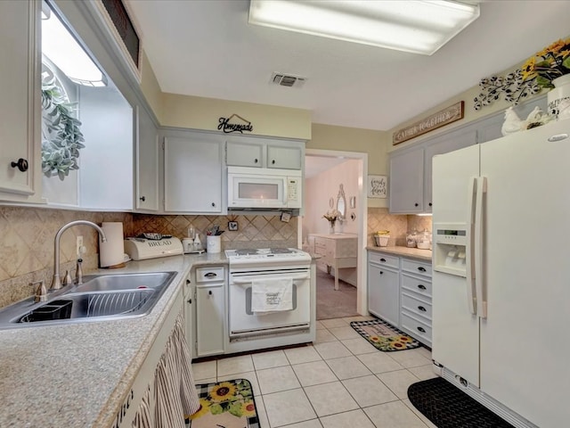 kitchen featuring visible vents, light countertops, light tile patterned flooring, white appliances, and a sink