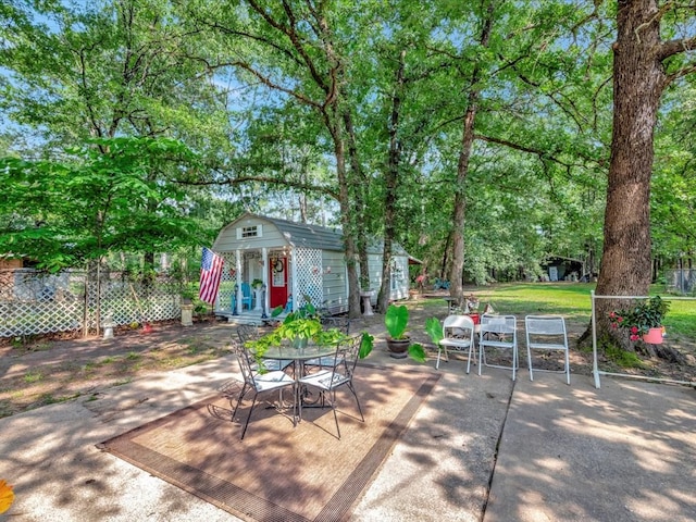 view of patio featuring outdoor dining space, an outdoor structure, and fence