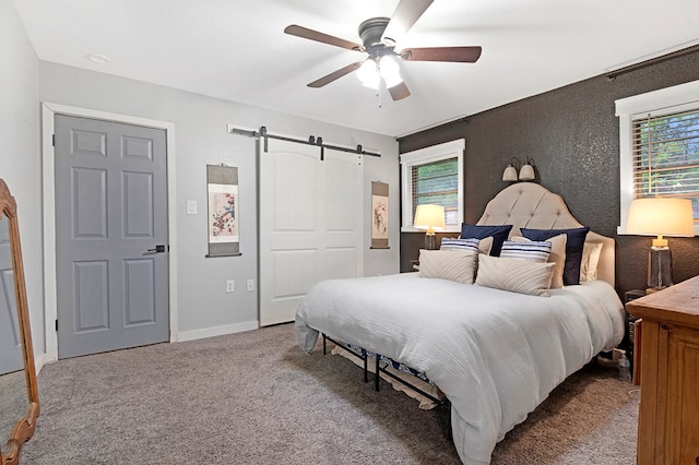 carpeted bedroom featuring baseboards, ceiling fan, and a barn door