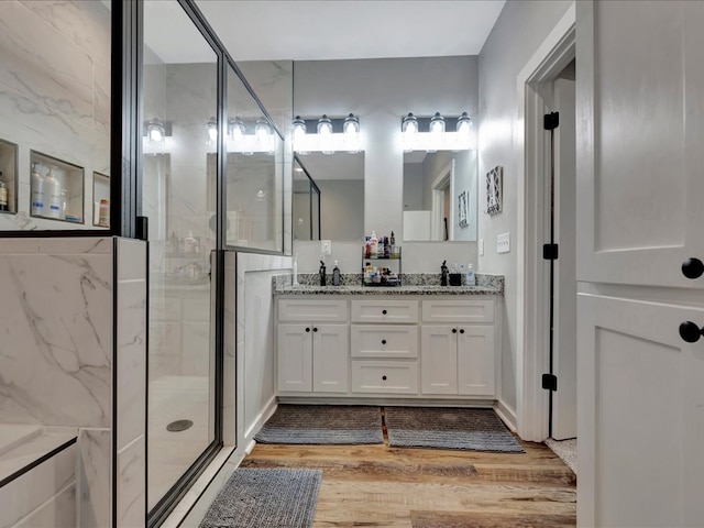 full bathroom with double vanity, wood finished floors, and a stall shower