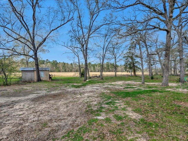 view of yard with an outbuilding, a shed, and a rural view