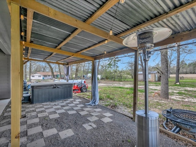 view of patio featuring a storage unit, an outbuilding, and a hot tub