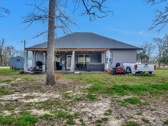 rear view of house featuring a patio area, a hot tub, and roof with shingles