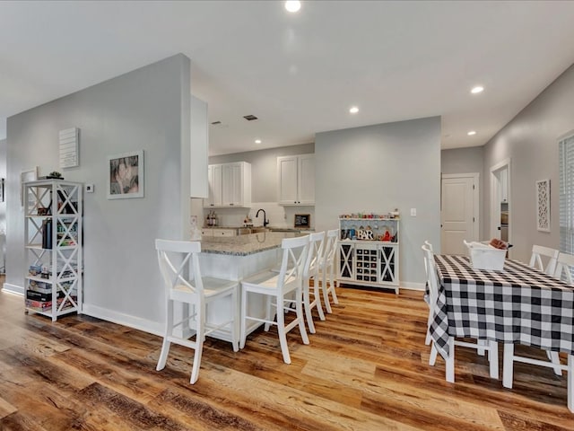 dining space with light wood-style flooring, recessed lighting, and baseboards