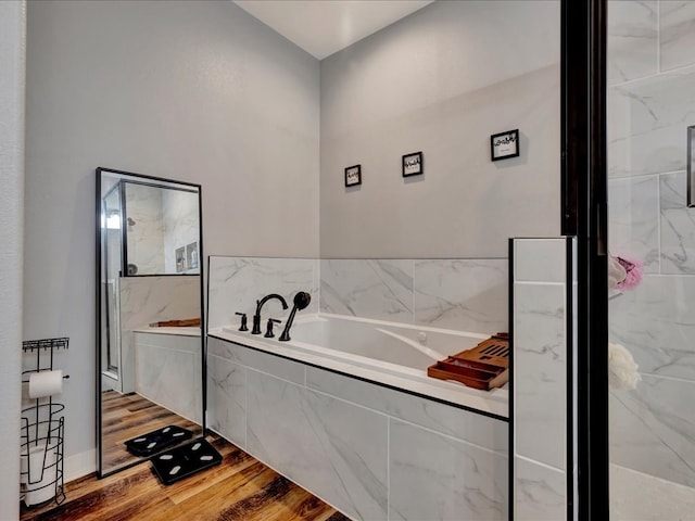 bathroom featuring a garden tub, wood finished floors, and a marble finish shower