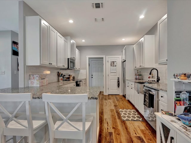 kitchen with light wood-style flooring, visible vents, appliances with stainless steel finishes, and a sink