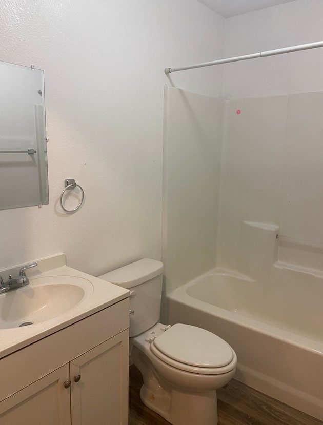 full bathroom with shower / washtub combination, toilet, vanity, and hardwood / wood-style flooring