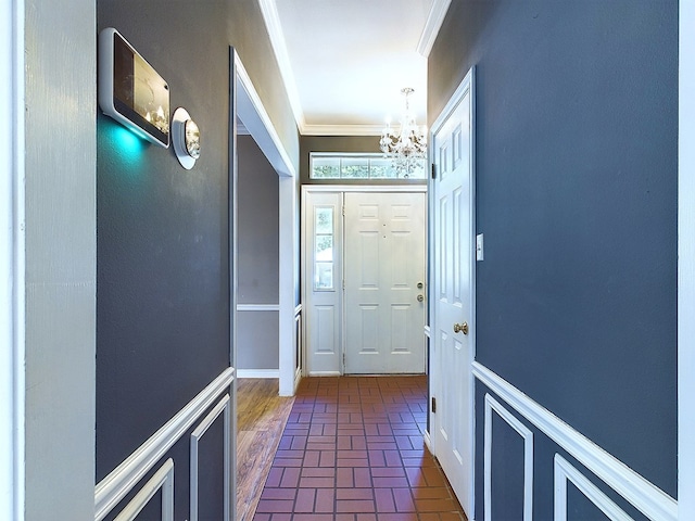 entryway featuring crown molding and an inviting chandelier