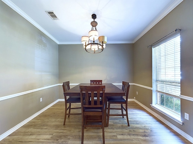 dining room featuring hardwood / wood-style flooring, an inviting chandelier, and crown molding