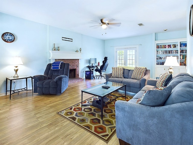 living room with ceiling fan, light wood-type flooring, and a fireplace