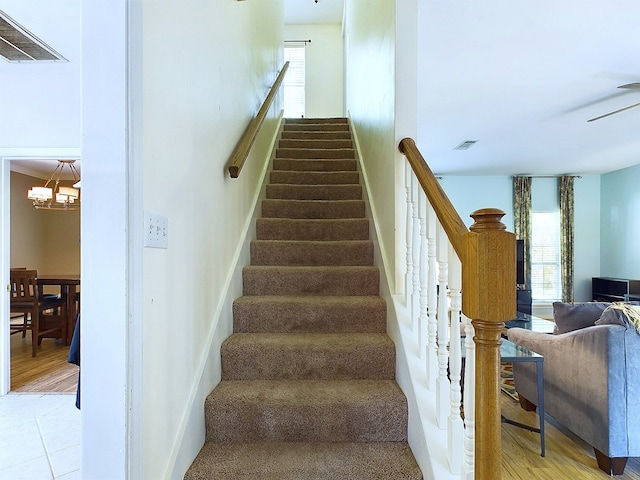 staircase with hardwood / wood-style floors, ornamental molding, and an inviting chandelier