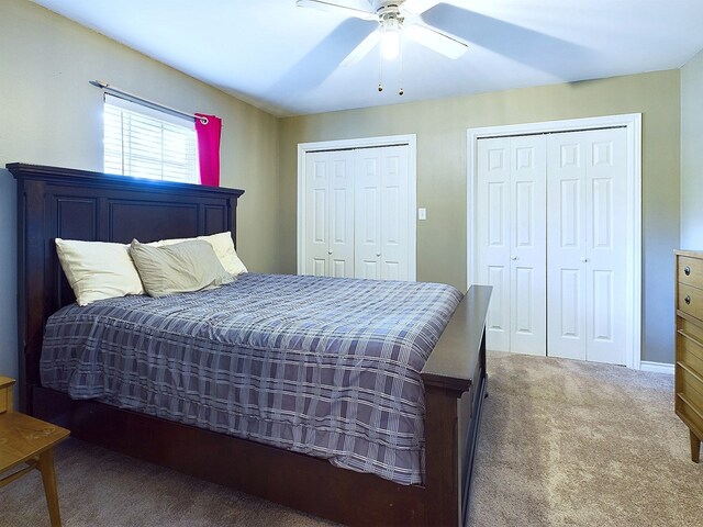 bedroom with carpet flooring, multiple closets, and ceiling fan