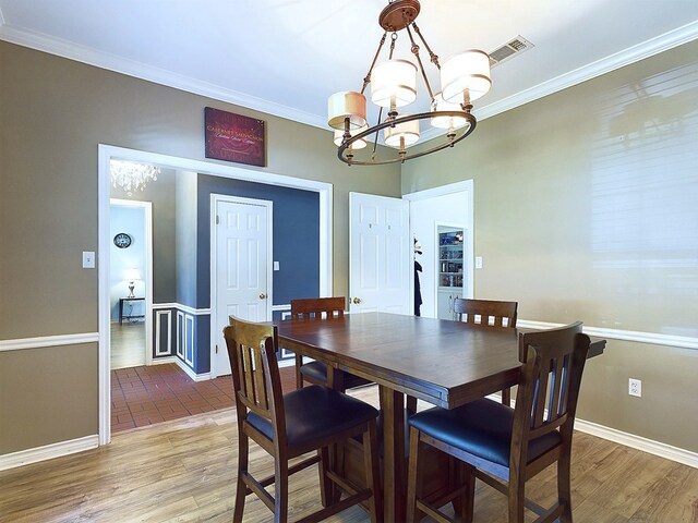 dining area with a chandelier, hardwood / wood-style floors, and crown molding