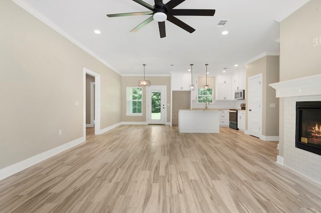 1911 Paul Ave, Lufkin, TX 75901 - unfurnished living room with a brick fireplace, a ceiling fan, crown molding, light wood-style floors, and recessed lighting