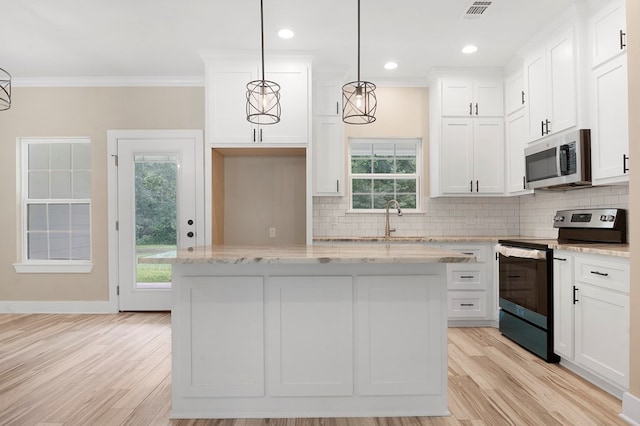 1911 Paul Ave, Lufkin, TX 75901 - kitchen with appliances with stainless steel finishes, crown molding, decorative backsplash, white cabinetry, and a center island