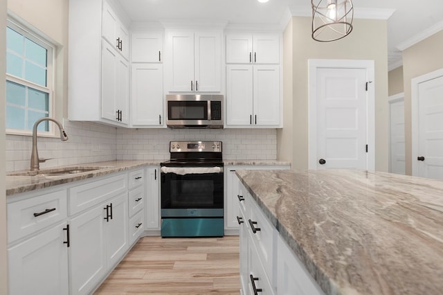 1911 Paul Ave, Lufkin, TX 75901 - kitchen featuring appliances with stainless steel finishes, ornamental molding, light wood-style flooring, white cabinetry, and tasteful backsplash