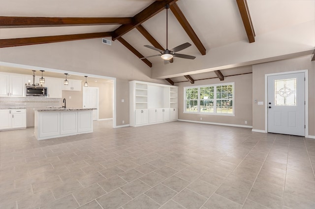 unfurnished living room with ceiling fan, sink, light tile patterned floors, high vaulted ceiling, and beamed ceiling