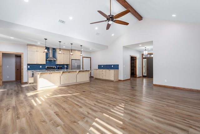 1308 Walnut Bend Dr, Lufkin, TX 75904 - kitchen featuring stainless steel refrigerator, wall chimney range hood, light brown cabinetry, a breakfast bar, and beam ceiling