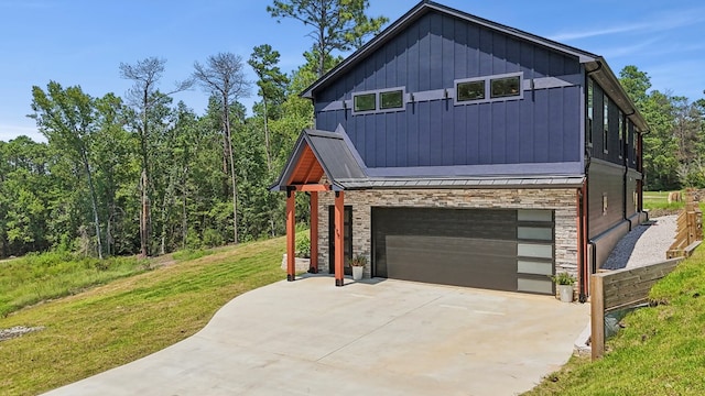 175 Vantage Dr, Brookeland, TX 75931 - view of home's exterior with stone siding, an attached garage, a lawn, concrete driveway, and a standing seam roof