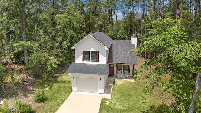 140 Spruce Ln, Brookeland, TX 75931 - view of front of home featuring driveway, a chimney, an attached garage, a front yard, and board and batten siding