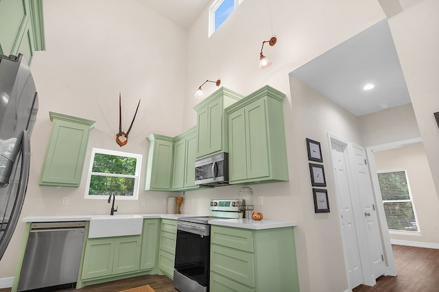 140 Spruce Ln, Brookeland, TX 75931 - kitchen with appliances with stainless steel finishes, green cabinetry, light countertops, dark wood finished floors, and a towering ceiling