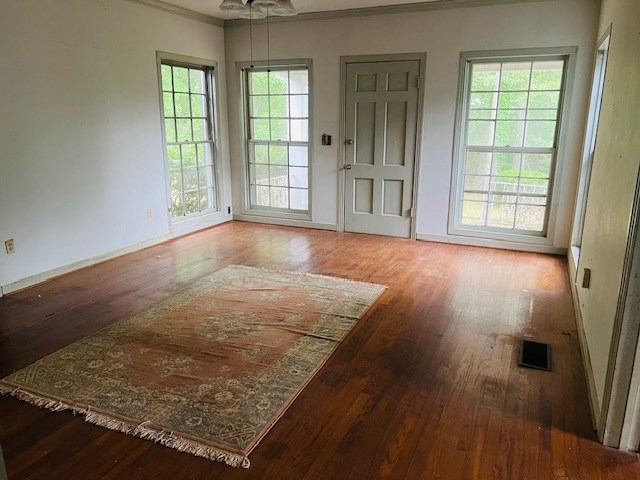 905 Fm 353, San Augustine, TX 75972 - doorway to outside featuring wood-type flooring, visible vents, baseboards, and ornamental molding