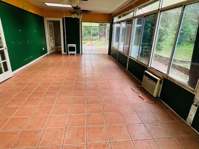 905 Fm 353, San Augustine, TX 75972 - unfurnished sunroom featuring ceiling fan, heating unit, a wall unit AC, and tile patterned floors